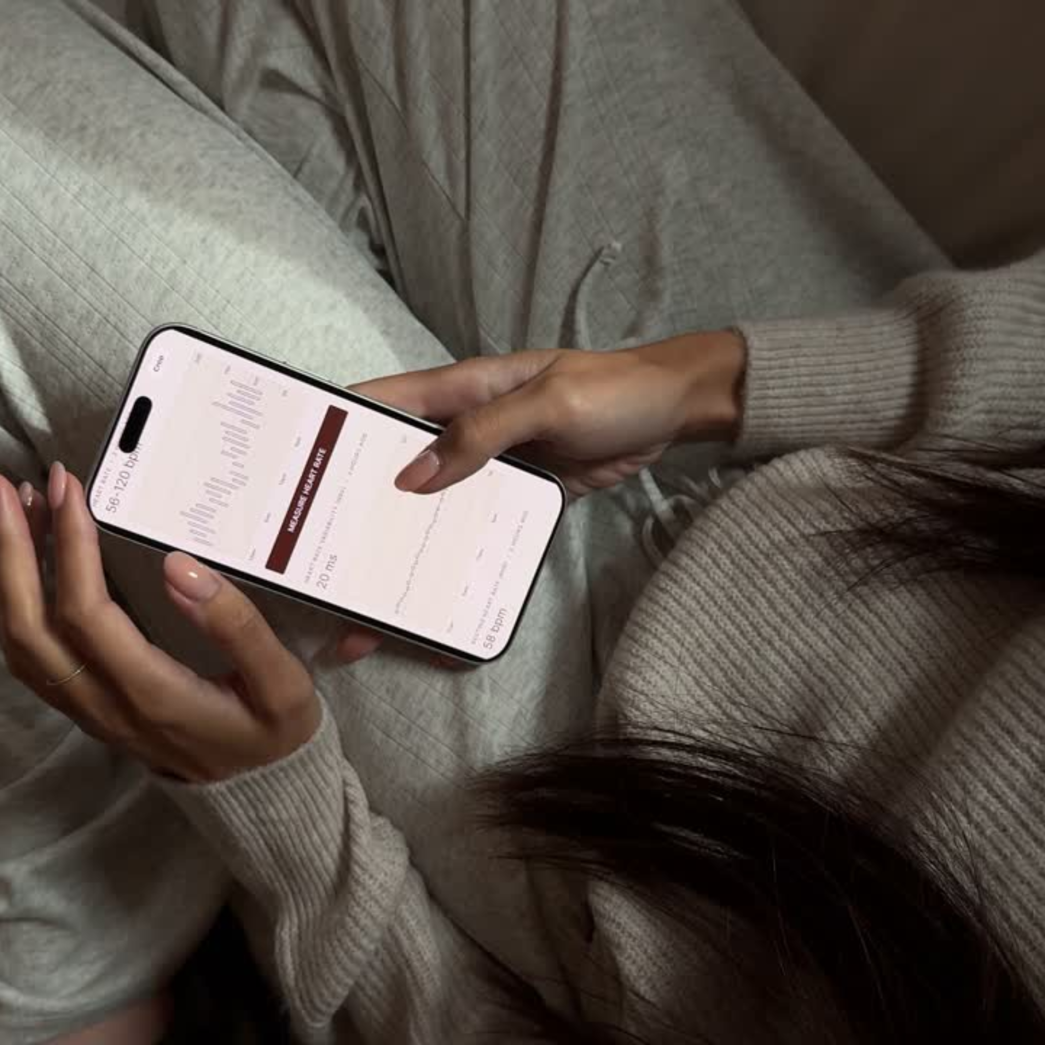 A woman holds a smartphone open to the Heart metrics in the Petal health app