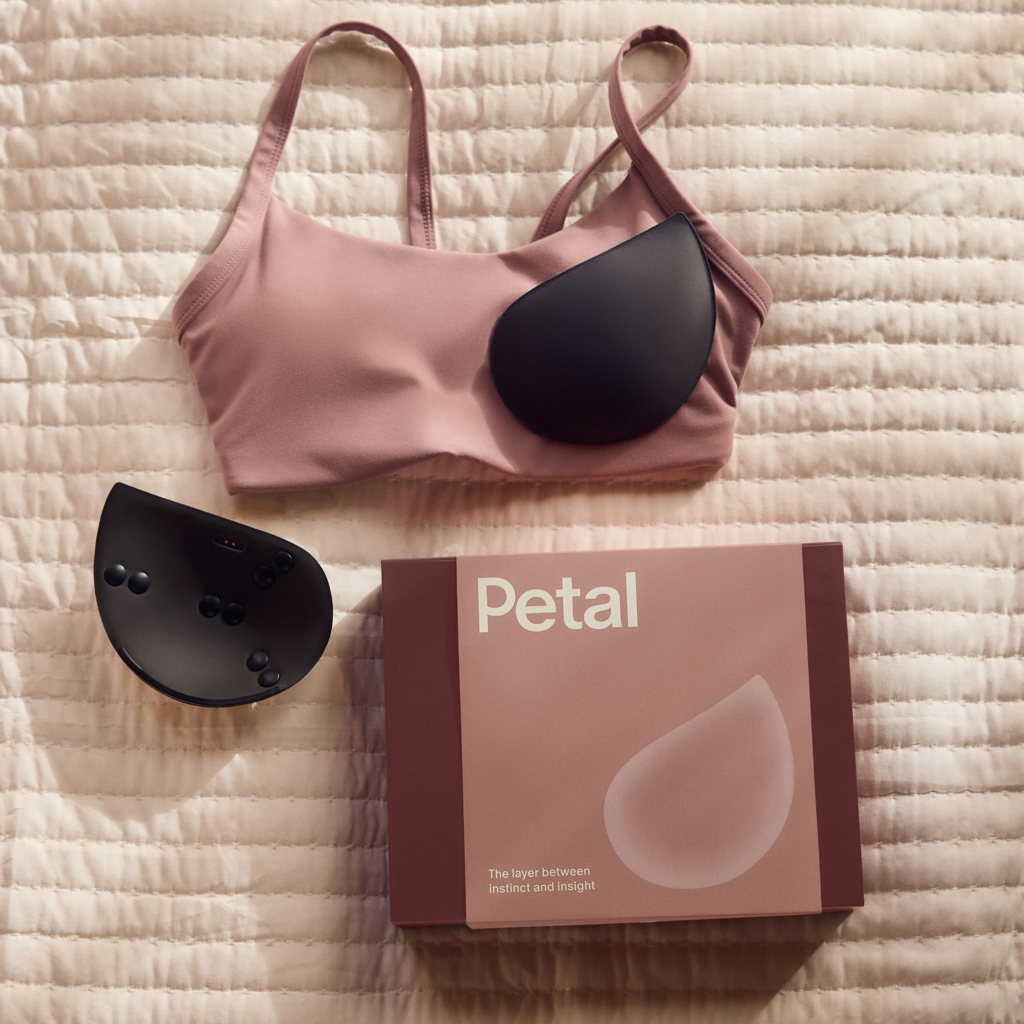 Pink bra with black Petal smart inserts and 'Petal' box on a textured surface