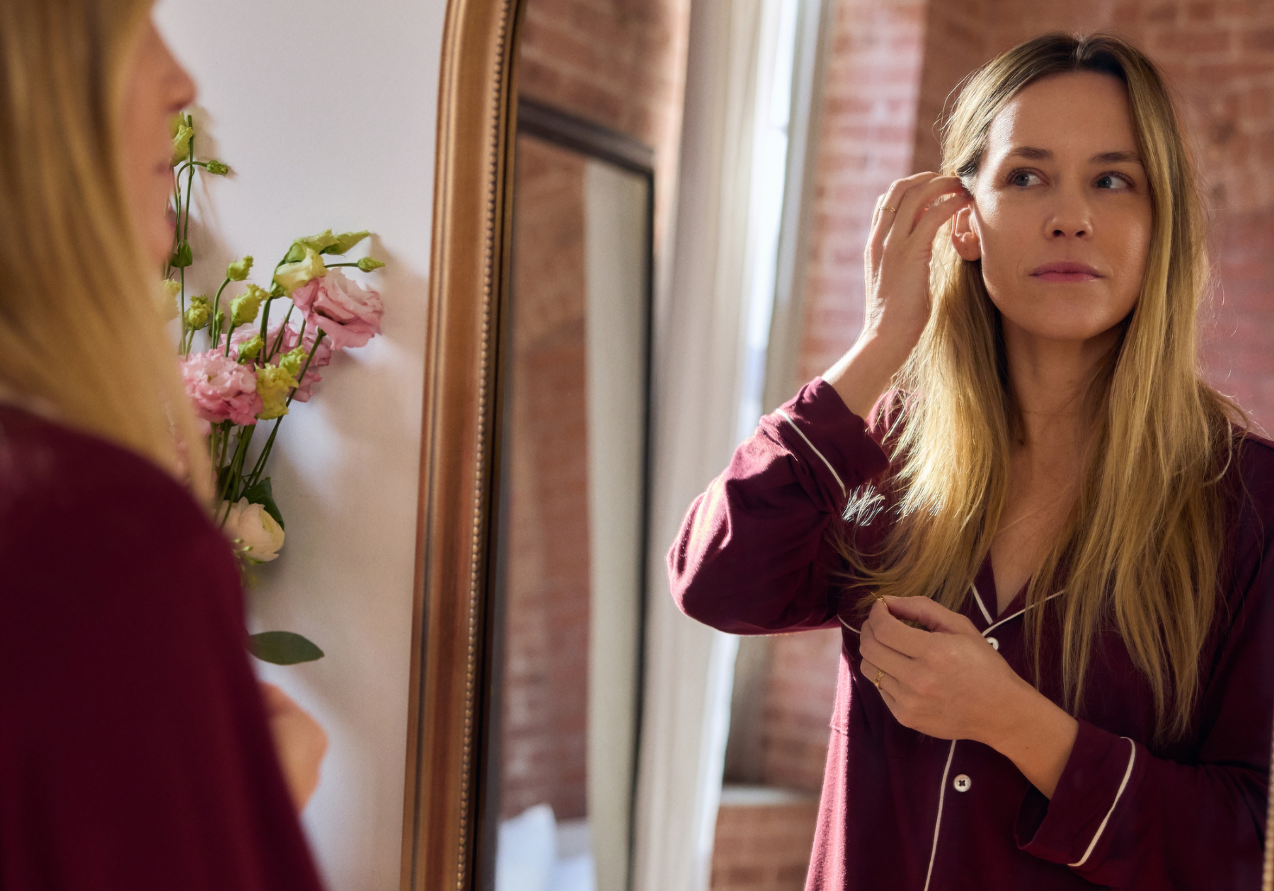 Woman adjusting her hair in front of a mirror 